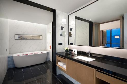 a bathroom with a tub and a large mirror at Yiho Hotel Mawei Fuzhou in Fuzhou