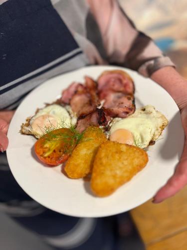 a person holding a white plate of food at Adventure Lodge and Motels and Tongariro Crossing Track Transport in National Park