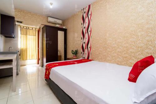 a bedroom with a bed with a red and white canopy at RedLiving Apartemen Green Lake View Ciputat - Hanna Property Tower B in Pondokcabe Hilir