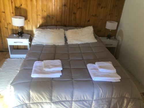 1 cama con 2 toallas y 2 mesitas de noche en El Amparo en Esquel