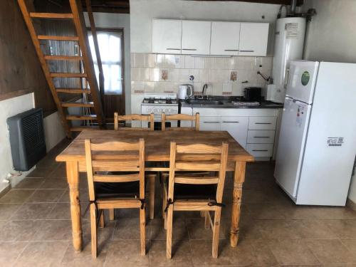 cocina con mesa de madera con sillas y nevera en El Amparo en Esquel