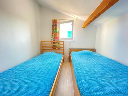Duas camas num pequeno quarto com uma janela em Maison Bretignolles-sur-Mer, 2 pièces, 4 personnes - FR-1-231-142 em Bretignolles-sur-Mer