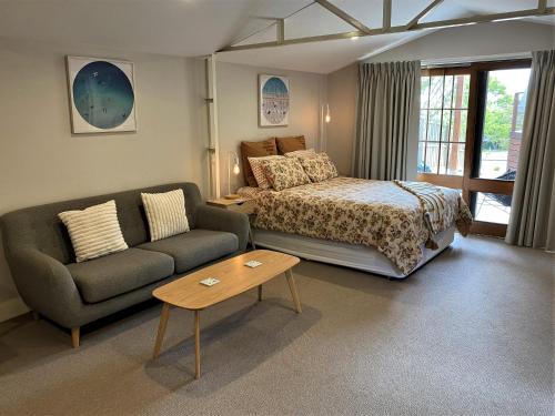 a bedroom with a bed and a couch and a table at The Cosy Bungalow in Portarlington