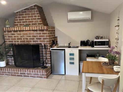 a kitchen with a brick fireplace next to a table at The Cosy Bungalow in Portarlington