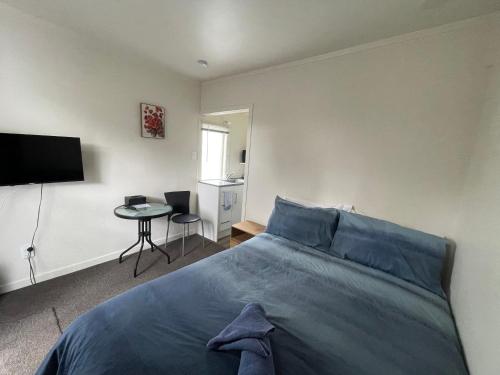 a bedroom with a bed and a table and a television at Summer Inn Motel in Orewa