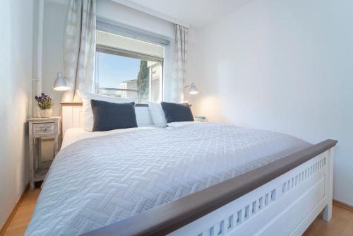 a white bedroom with a large bed with a window at Hanseat Sonnenglück in Grömitz