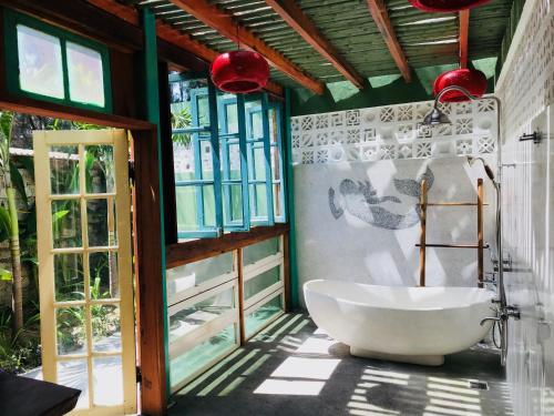 Salt Villa 3BR Oceanview An Bang Beach Hoi An في An Bàn: حمام مع حوض استحمام أبيض في غرفة مع نوافذ