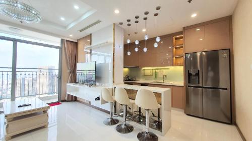 a kitchen with a counter with stools and a refrigerator at Vinhome Central Park Apartment in Ho Chi Minh City