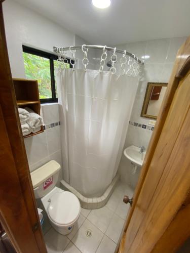 a bathroom with a toilet and a shower curtain at La Peregrina Galapagos B&B in Puerto Ayora
