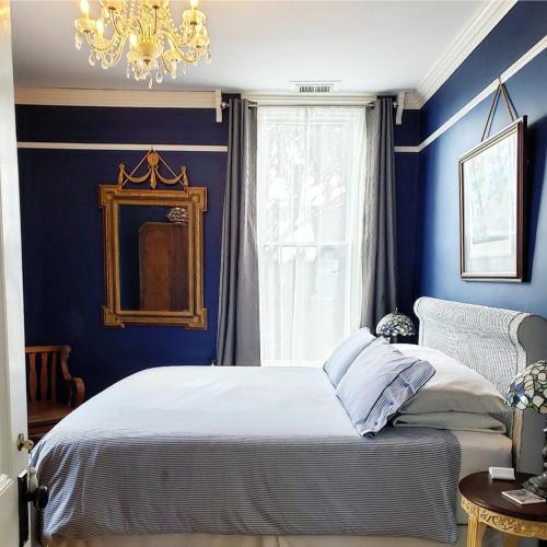 a blue bedroom with a bed and a chandelier at South Court Inn in Luray