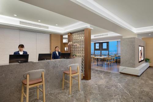 two women standing at a counter in a hotel lobby at Joysuites Nantong in Nantong