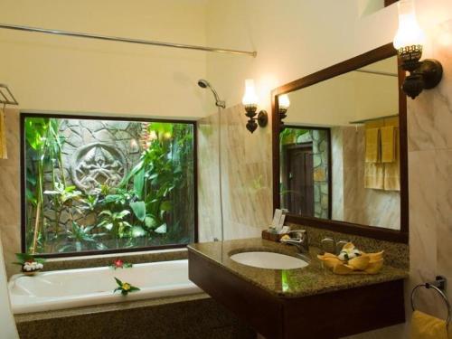 La salle de bains est pourvue d'une baignoire, d'un lavabo et d'un miroir. dans l'établissement Cham Villas Resort, à Mui Ne