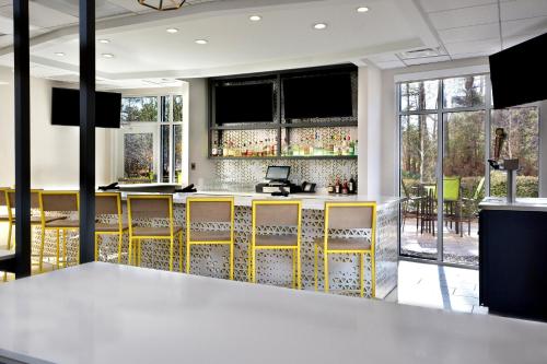 a bar with yellow accents in a room with windows at Holiday Inn Raleigh Durham Airport by IHG in Morrisville