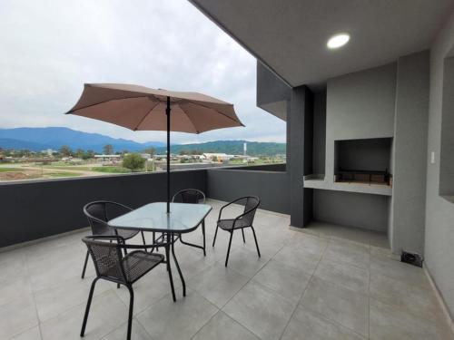 a table and chairs with an umbrella on a balcony at ML NORTE Departamento in San Salvador de Jujuy