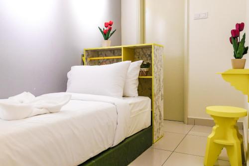 um quarto com uma cama com lençóis brancos e um banco amarelo em Arte Mont Kiara Homestay em Kuala Lumpur