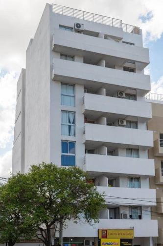 a tall white building with a tree in front of it at Departamento para cuatro personas in Cordoba