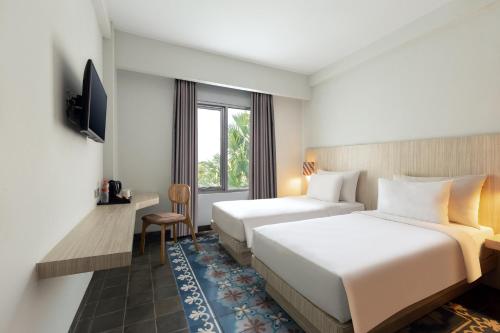 um quarto de hotel com duas camas e uma televisão em Burza Hotel Yogyakarta em Yogyakarta