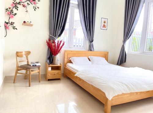 a bedroom with a bed and a chair and windows at Môn Bạc Home in Da Lat
