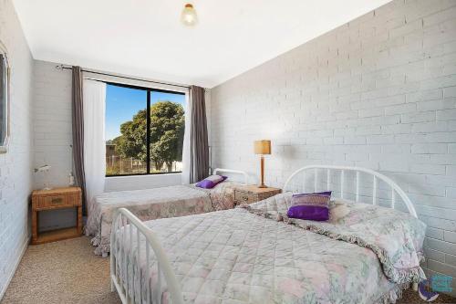 a bedroom with two beds and a large window at Apollo Unit 15 1st Floor in Narooma