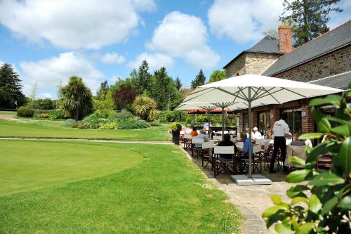 a group of people sitting at tables under an umbrella at Cottages De La Bretesche in Missillac