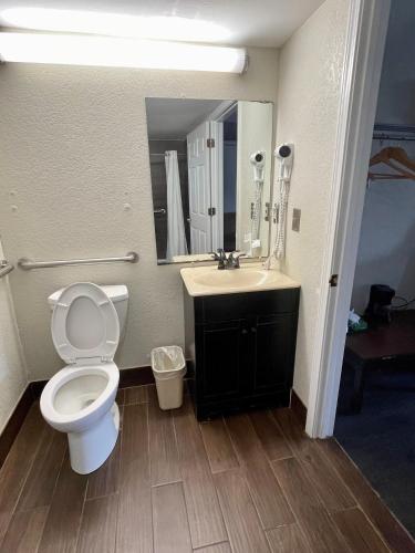 a bathroom with a toilet and a sink and a mirror at Key West Inn - Roanoke in Roanoke