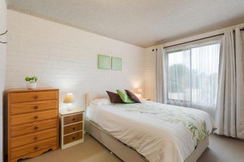 a bedroom with a bed with a dresser and a window at Apollo Unit 20 Ground Floor in Narooma