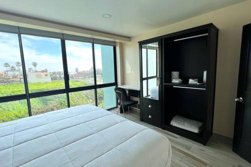 a bedroom with a bed and a desk and windows at Luxury 2BR Condo Rosarito (E) in Rosarito