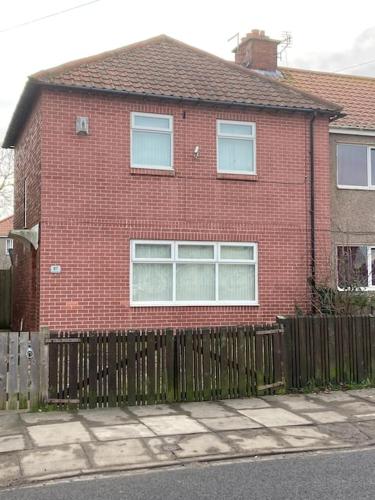 a red brick house with a wooden fence at Challoner House - sleeps 5 in Hartlepool