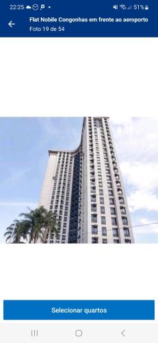 a tall white building with a palm tree in front of it at Nobile Congonhas in Sao Paulo