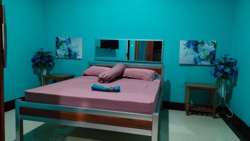 um quarto com uma cama com lençóis cor-de-rosa e uma parede azul em Jepun Bali hotel negara em Negara
