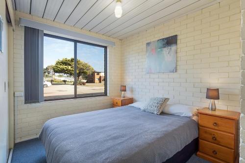 ein Schlafzimmer mit einem Bett und einem großen Fenster in der Unterkunft Apollo Unit 26 Ground Floor in Narooma