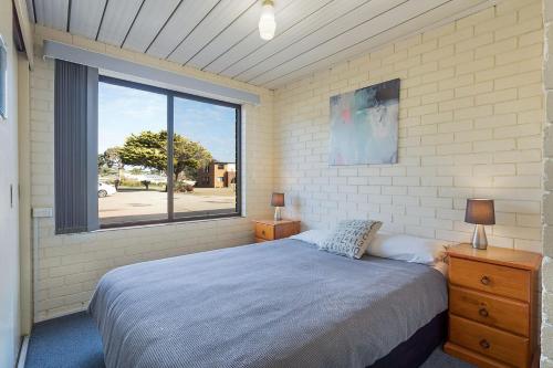 een slaapkamer met een bed en een groot raam bij Apollo Unit 26 Ground Floor in Narooma