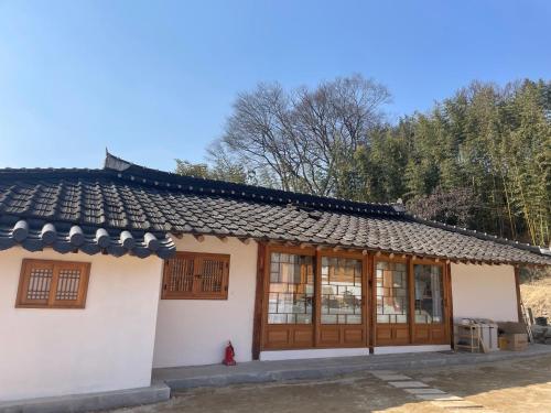 a small white building with wooden doors and windows at Hanok Stay - JukRokJungSa in Gurye