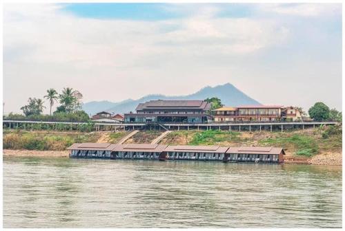 ein Boot auf einem Fluss mit Gebäuden im Hintergrund in der Unterkunft Riverside Chiangkhan in Ban Mai Ta Saeng