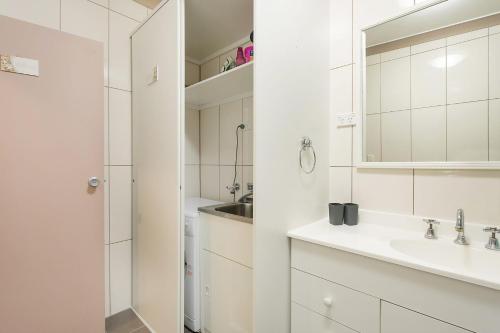 a white bathroom with a sink and a mirror at Apollo Unit 7 1st Floor in Narooma