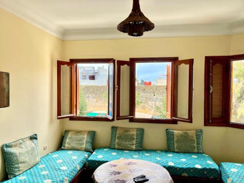a living room with a couch and two windows at soleado apartamento al lado de la preciosa medina , a 3 minutos de la playa andando I in Asilah
