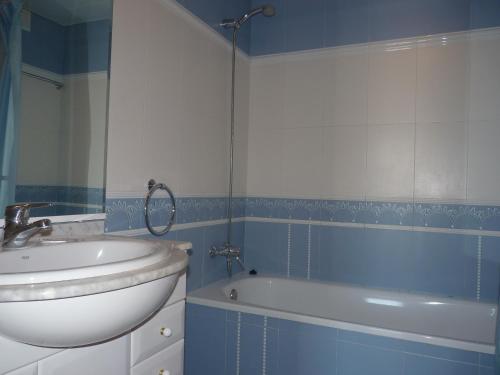 baño azul y blanco con lavabo y bañera en JOYAPARTMENTS La Joya, en Miami Platja