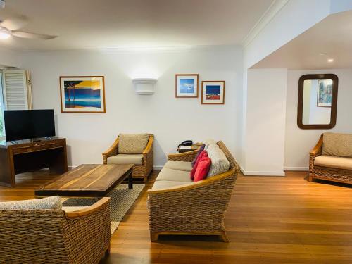 a living room with chairs and a table and a tv at BeachView Apartments at Villa Paradiso in Palm Cove