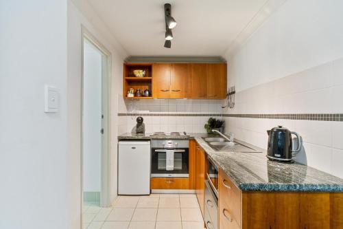 a kitchen with wooden cabinets and a counter top at Perth City Retreat - parking, pool, self contained in Perth