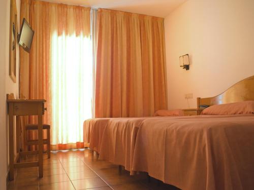 a bedroom with a bed and a window with orange curtains at Hotel Parc in Roses