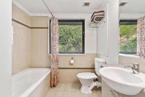 a bathroom with a tub and a toilet and a sink at Perth City Retreat - parking, pool, self contained in Perth