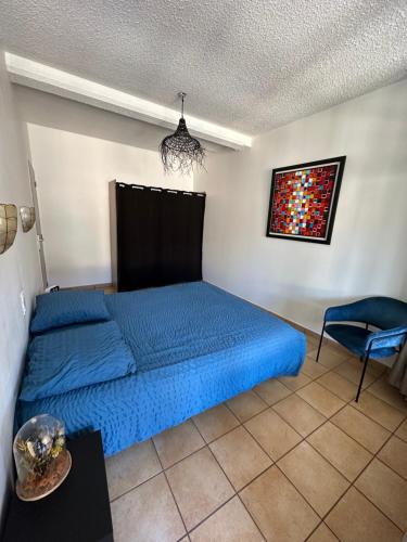 - une chambre avec un lit bleu et une chaise dans l'établissement L’instant Valsois, à Vals-les-Bains