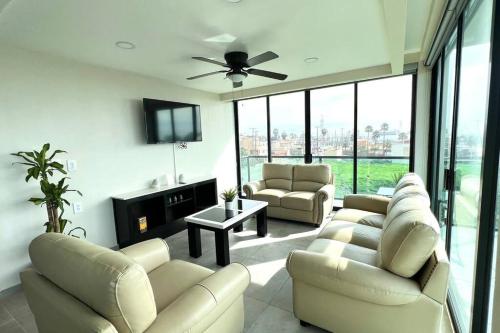 a living room with couches and a flat screen tv at Luxury 2BR Condo Rosarito (G) in Rosarito