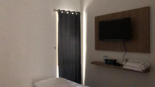 a bedroom with a window with a curtain and a television at Damai Guest House Cirebon in Cirebon