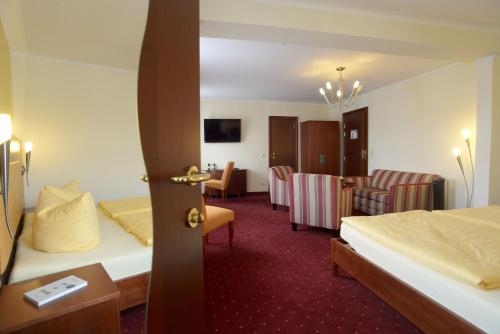 a hotel room with two beds and a table and chairs at Hotel Arena City in Leipzig