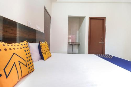 a bedroom with a large white bed with yellow pillows at OYO Spring Woods Suites in Sohāna