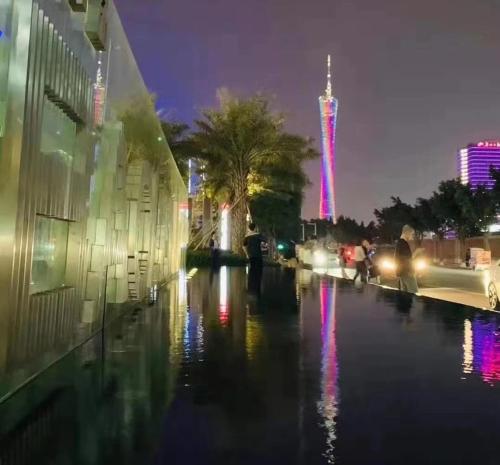 a flooded street at night with a tall building at Guangzhou He She Art Apartment in Guangzhou