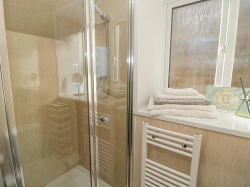 a bathroom with a shower and a sink with towels at The Apartment in Longframlington
