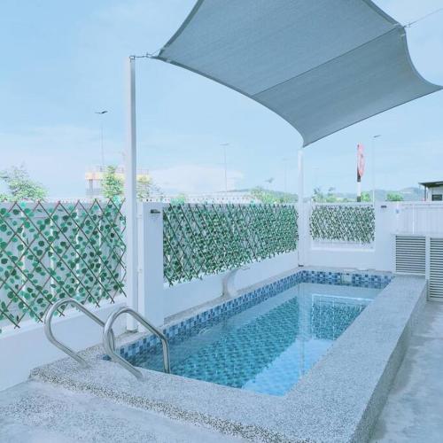 a swimming pool with an umbrella at Prima Guest House - Puncak Alam Homestay Mus-lim friendly in Bandar Puncak Alam