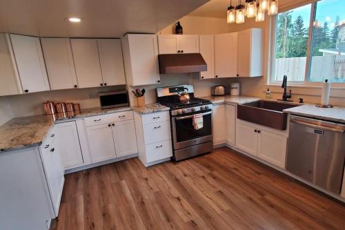 a kitchen with white cabinets and a stove top oven at Luxury DT Cottage - Free Parking - Self Check-In in Anchorage